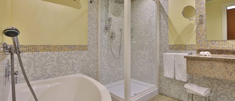 A bathroom with a glass-enclosed shower, a bathtub, and a vanity with a mirror.