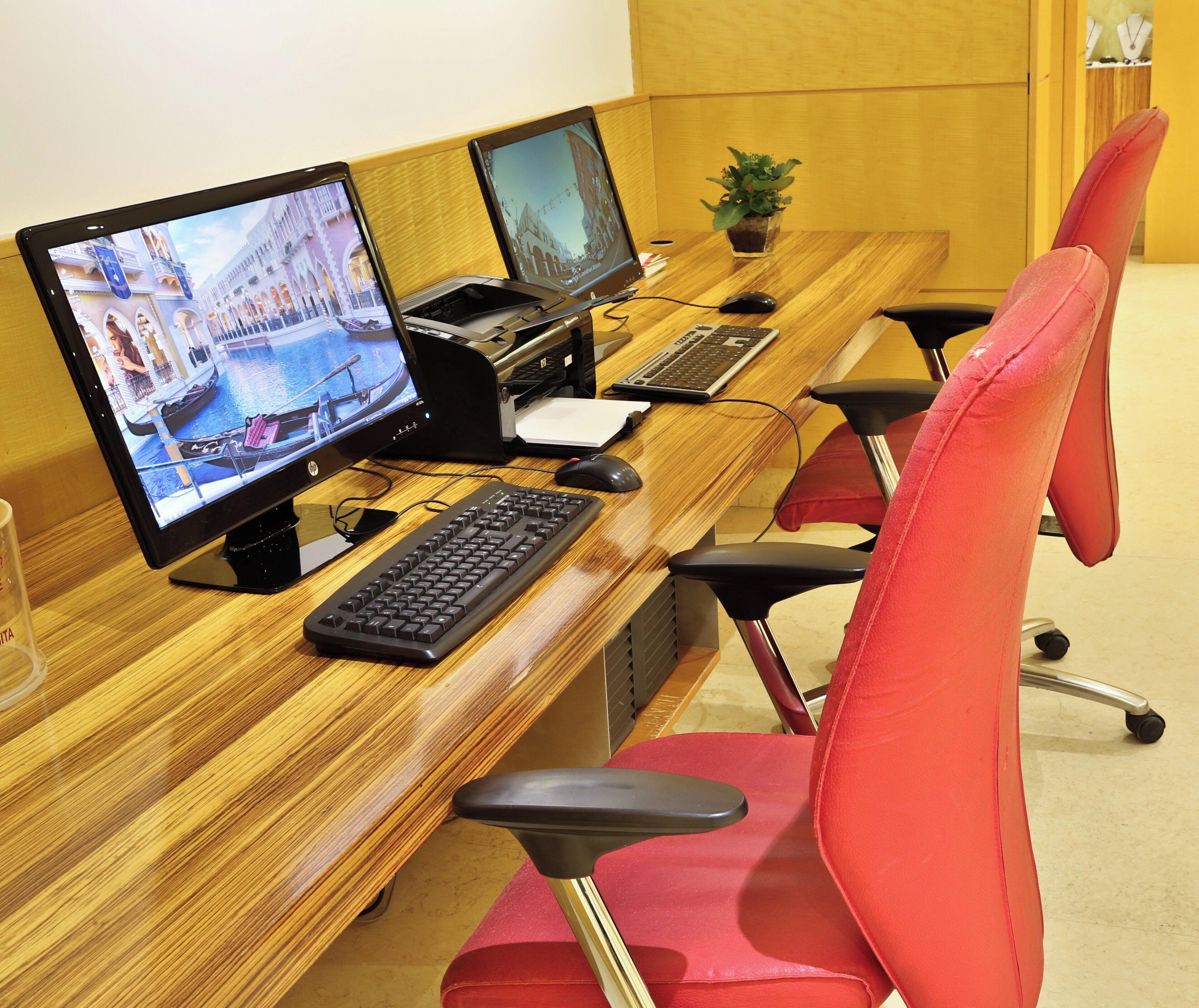 A long wooden desk with three computer monitors, a keyboard, and a mouse.