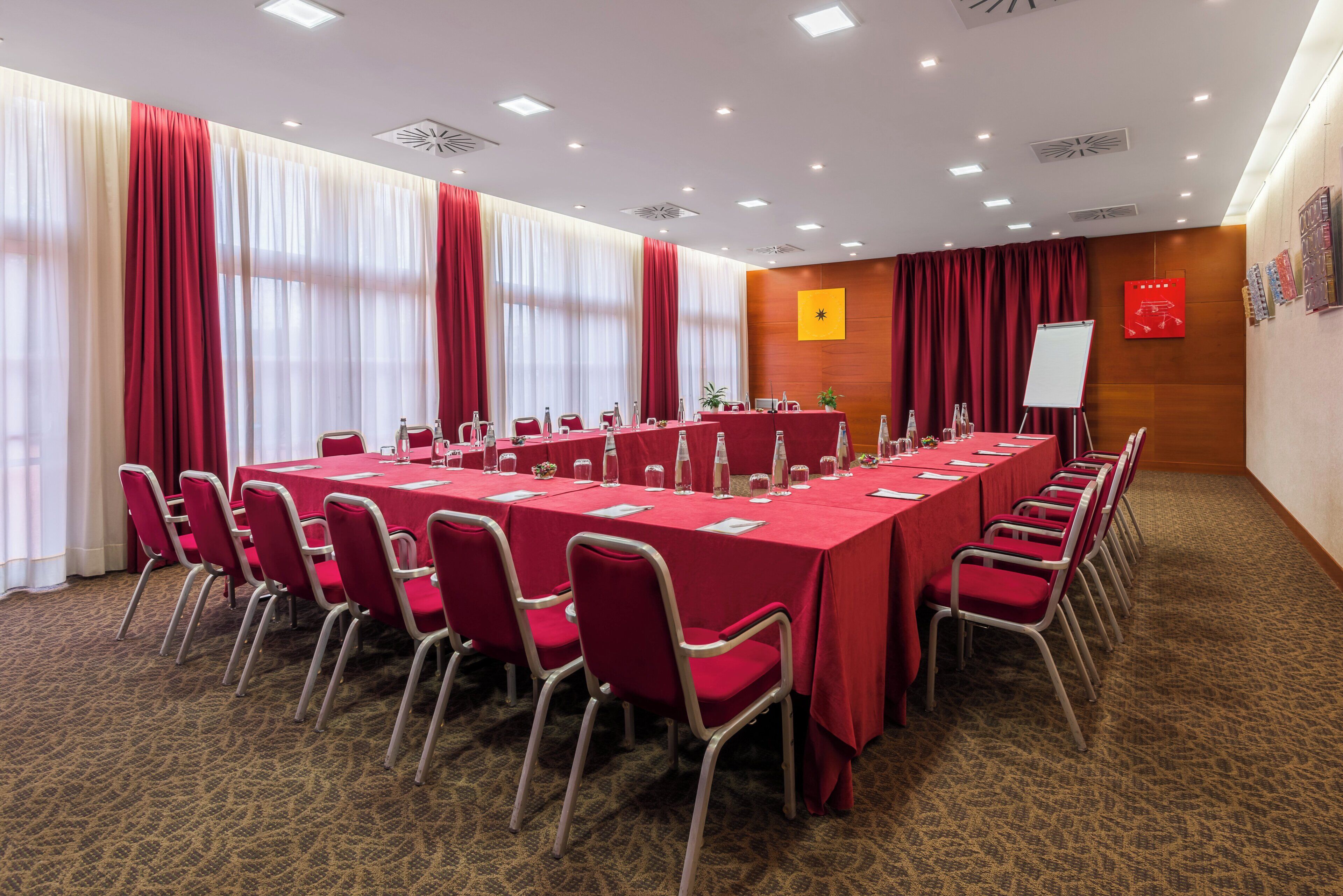 A conference room with a long table, red chairs, and a whiteboard.