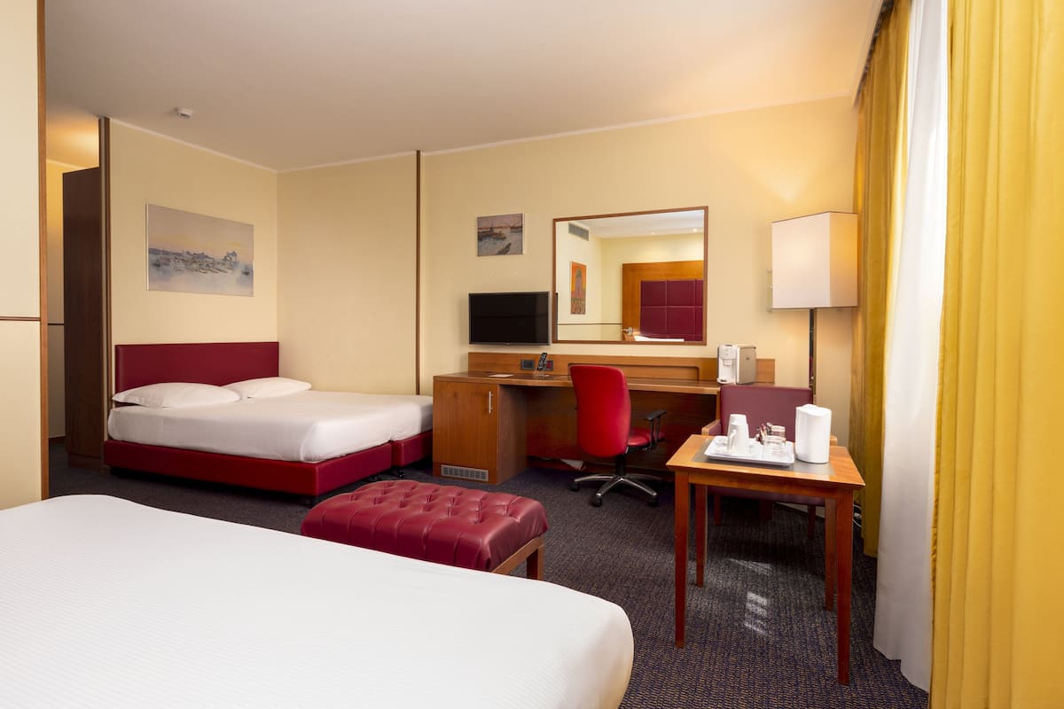 Ein Hotelzimmer mit einem Bett, einem Schreibtisch, einem Stuhl, einem Fernseher und einem Spiegel.