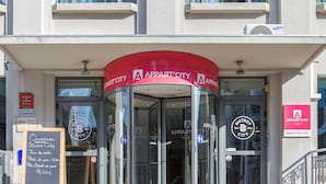 A building entrance with a red awning labeled "APPART'CITY" and glass revolving doors. - Appart'City Classic Lyon Part-Dieu (Lyon)