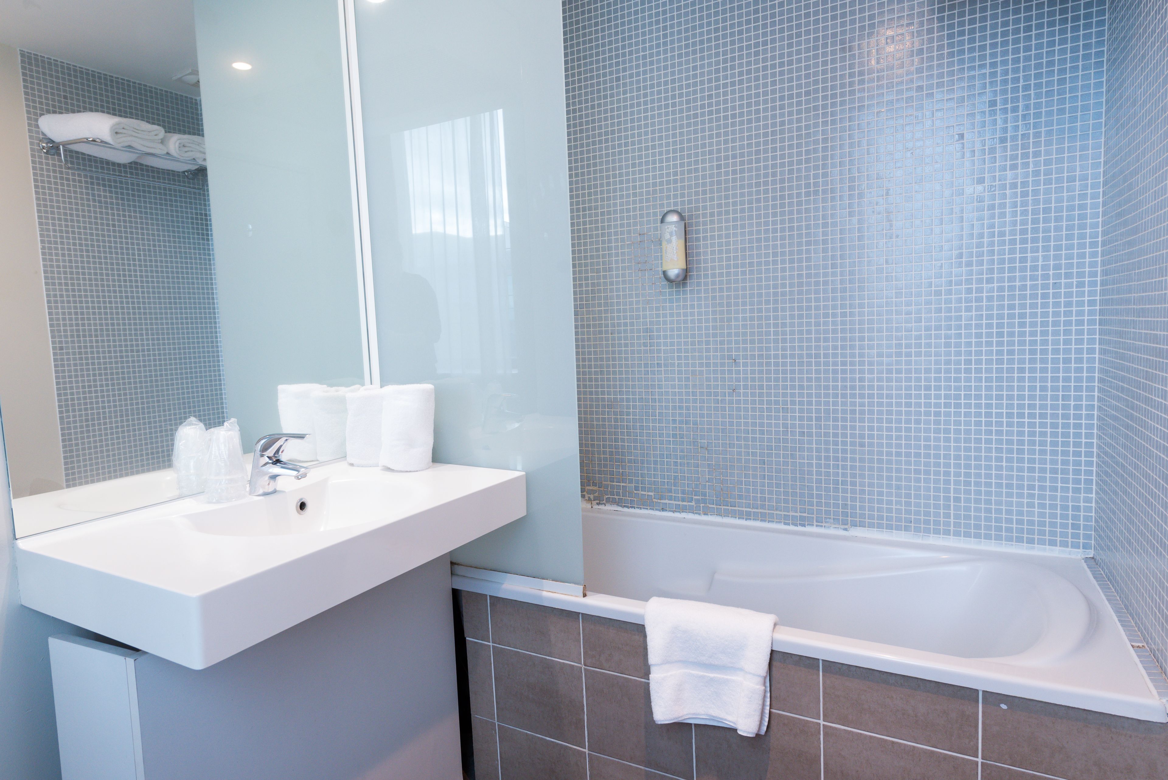 A modern bathroom with a white sink, mirror, and bathtub.