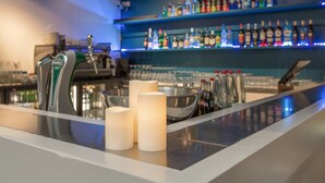A bar area with a beer tap, candles, and a variety of liquor bottles on shelves. - Appart'City Classic Lyon Part-Dieu (Lyon)