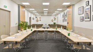 A conference room with a long table, chairs, and framed pictures on the walls. - Appart'City Classic Lyon Part-Dieu (Lyon)