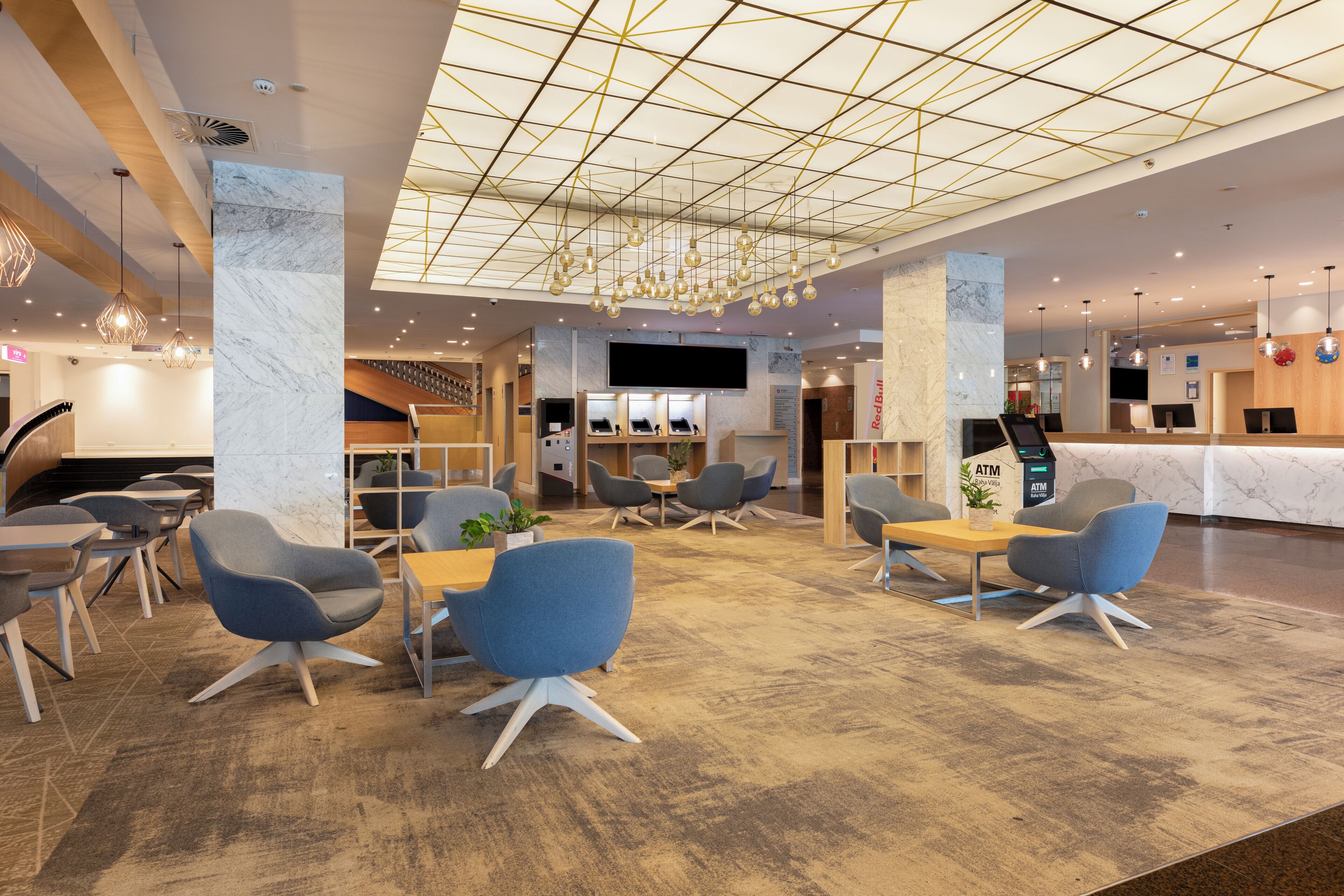 A modern lobby with a geometric ceiling design, seating areas, and a reception desk.