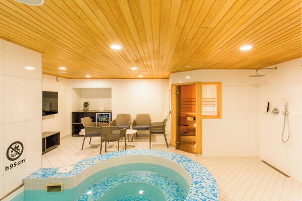 A spa area with a hot tub, seating, and a shower.