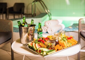 Una bandeja con comida y bebidas en una mesa cerca de la piscina.