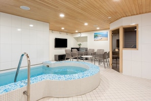 Zona de spa con hidromasaje, asientos y televisor.