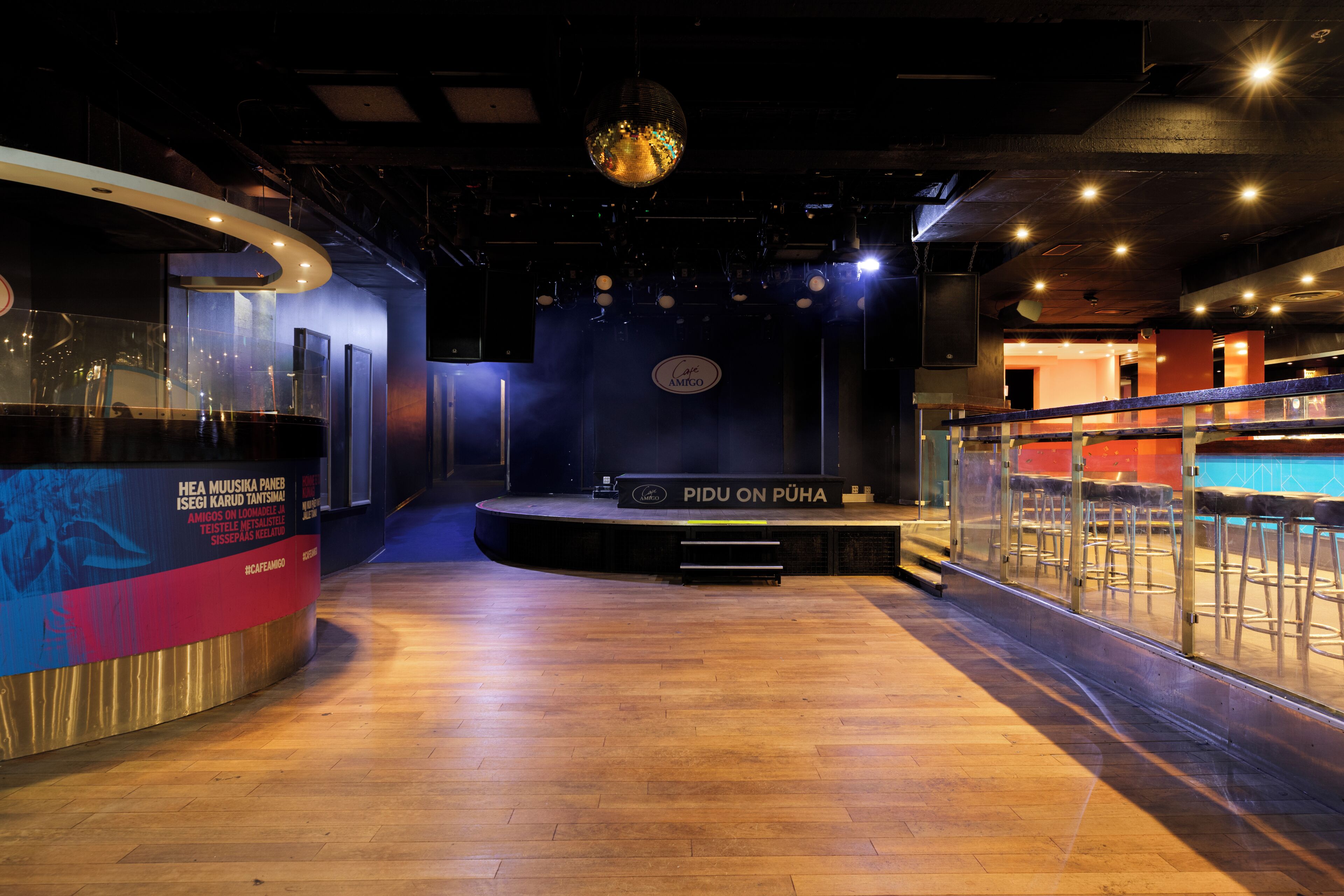 An indoor space with a stage, seating area, and a bar counter.