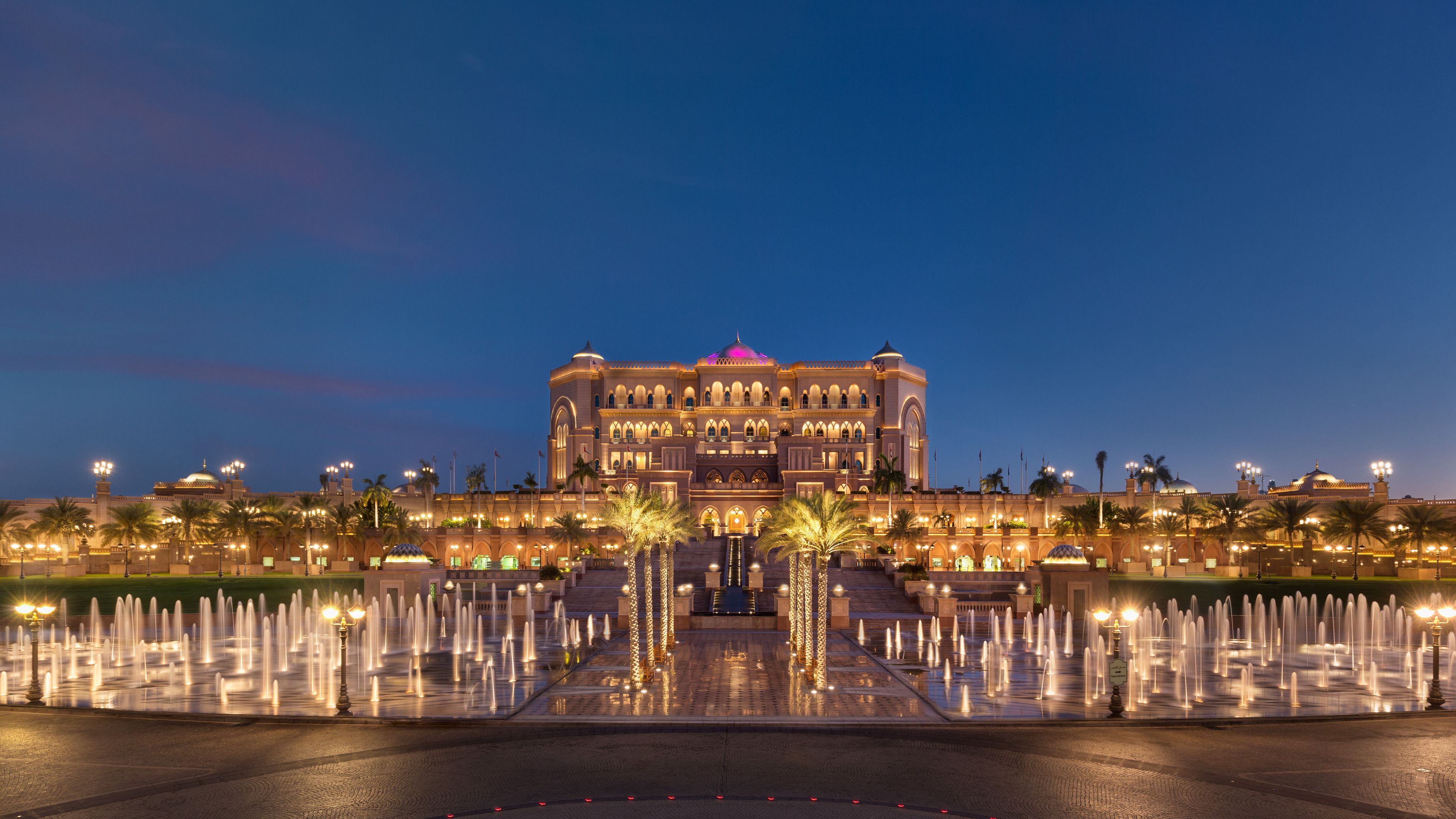 Un grand hôtel avec une vaste fontaine à l’entrée, de nombreux étages et un dôme imposant.