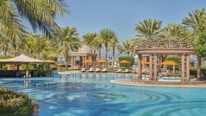 A swimming pool with lounge chairs and umbrellas, surrounded by palm trees and a gazebo structure. - Emirates Palace Mandarin Oriental, Abu Dhabi (Abu Dhabi)