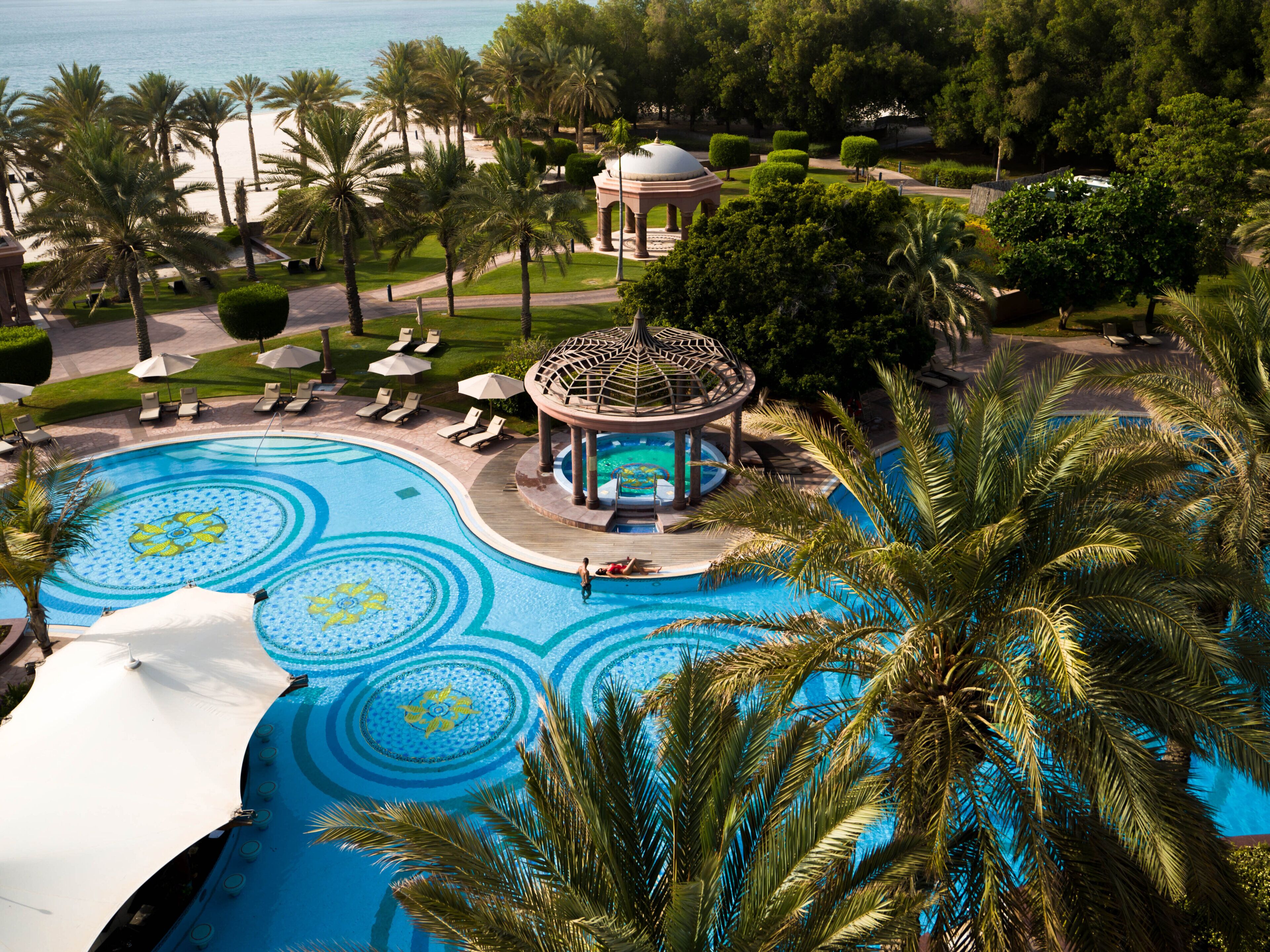 A large outdoor swimming pool with a gazebo and palm trees.