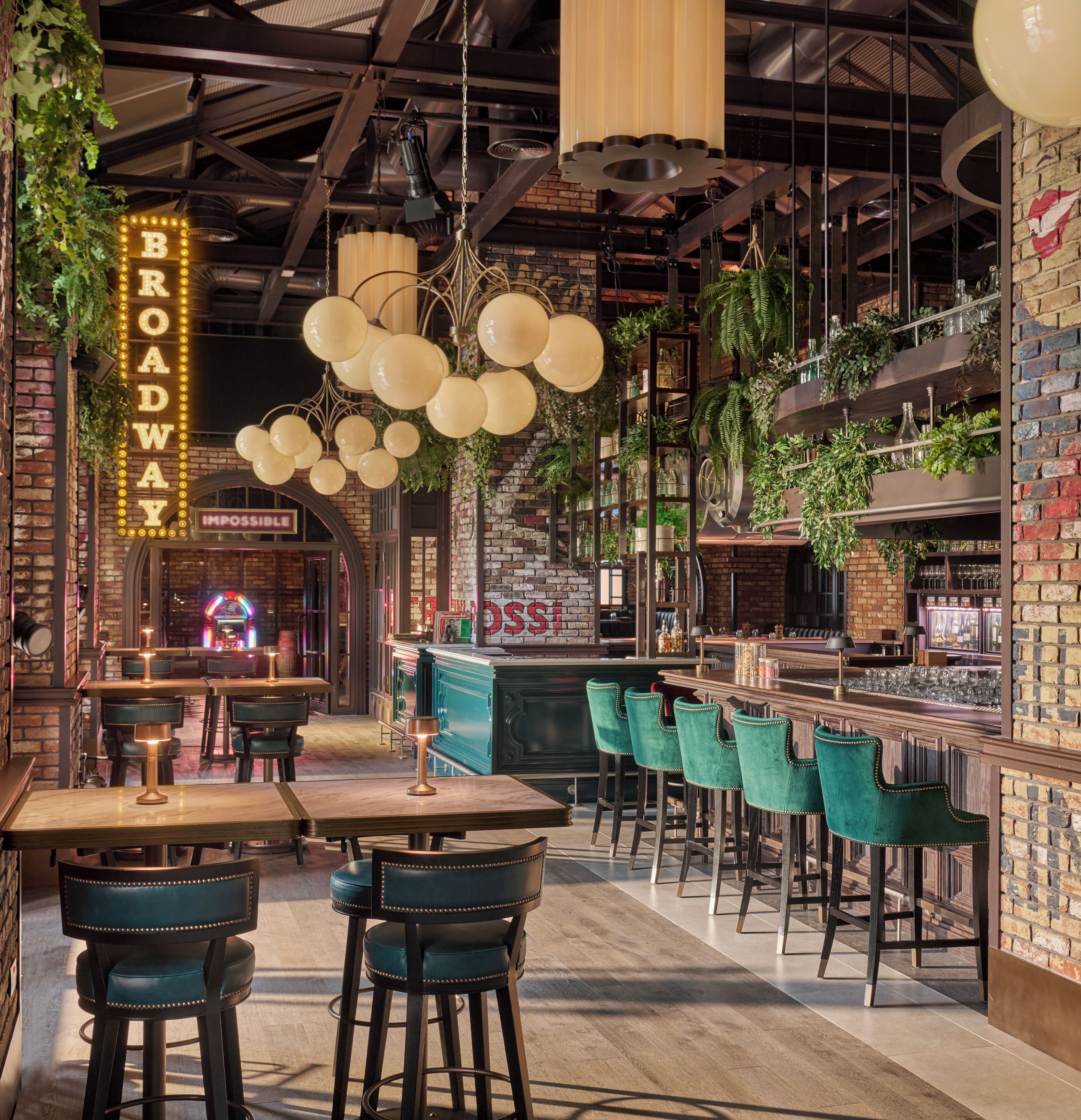 A bar area with high stools, a counter, and hanging light fixtures.