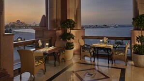 A luxurious balcony with ornate columns, elegant furniture, and a view of the sea and cityscape at dusk. - Emirates Palace Mandarin Oriental, Abu Dhabi (Abu Dhabi)