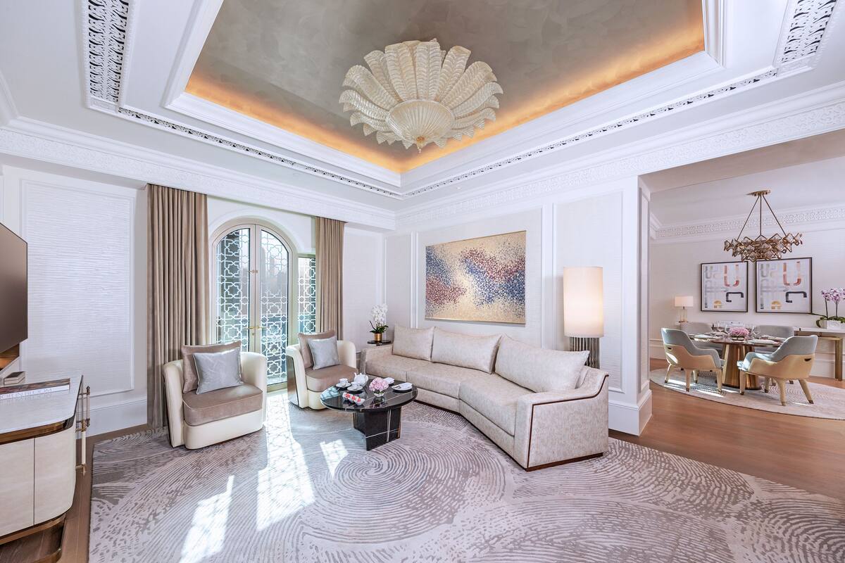 A spacious living room with a large sectional sofa, a coffee table, and a dining area with chairs and a table.