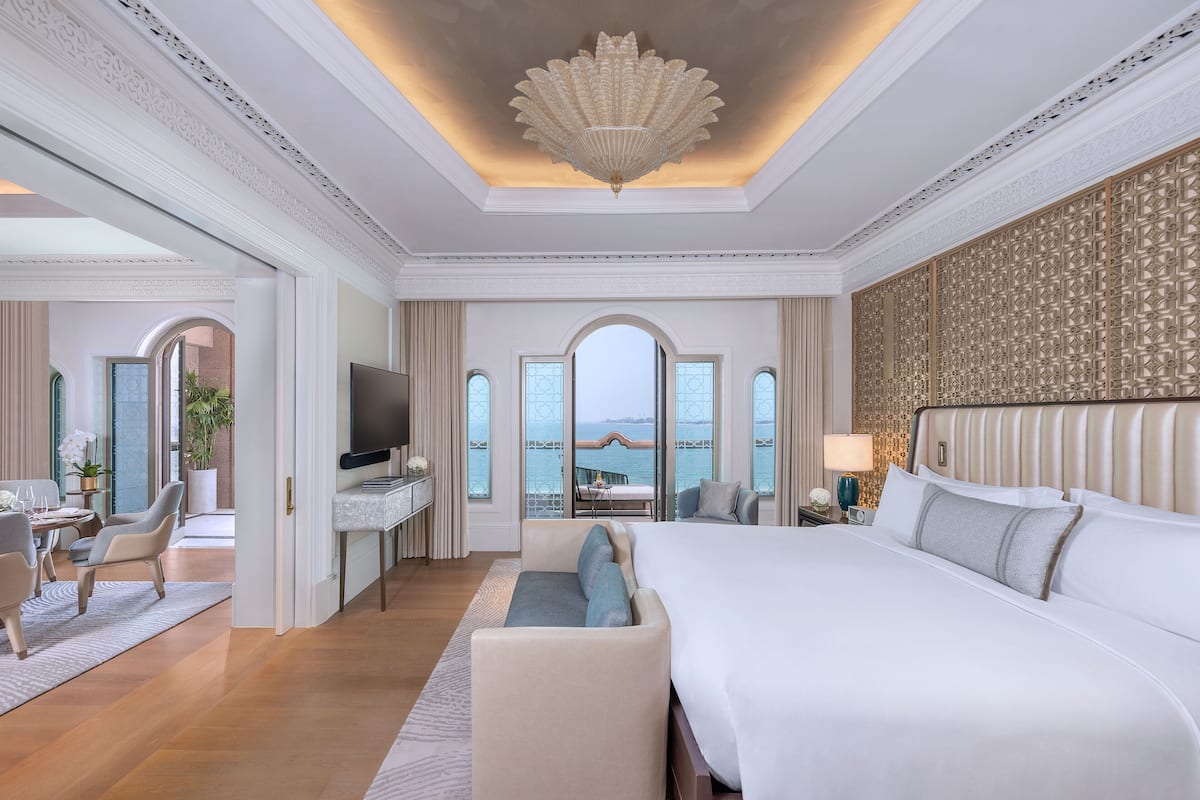 Ein luxuriöses Hotelzimmer mit einem großen Bett, einem Fernseher, einer Sitzecke und Meerblick.
