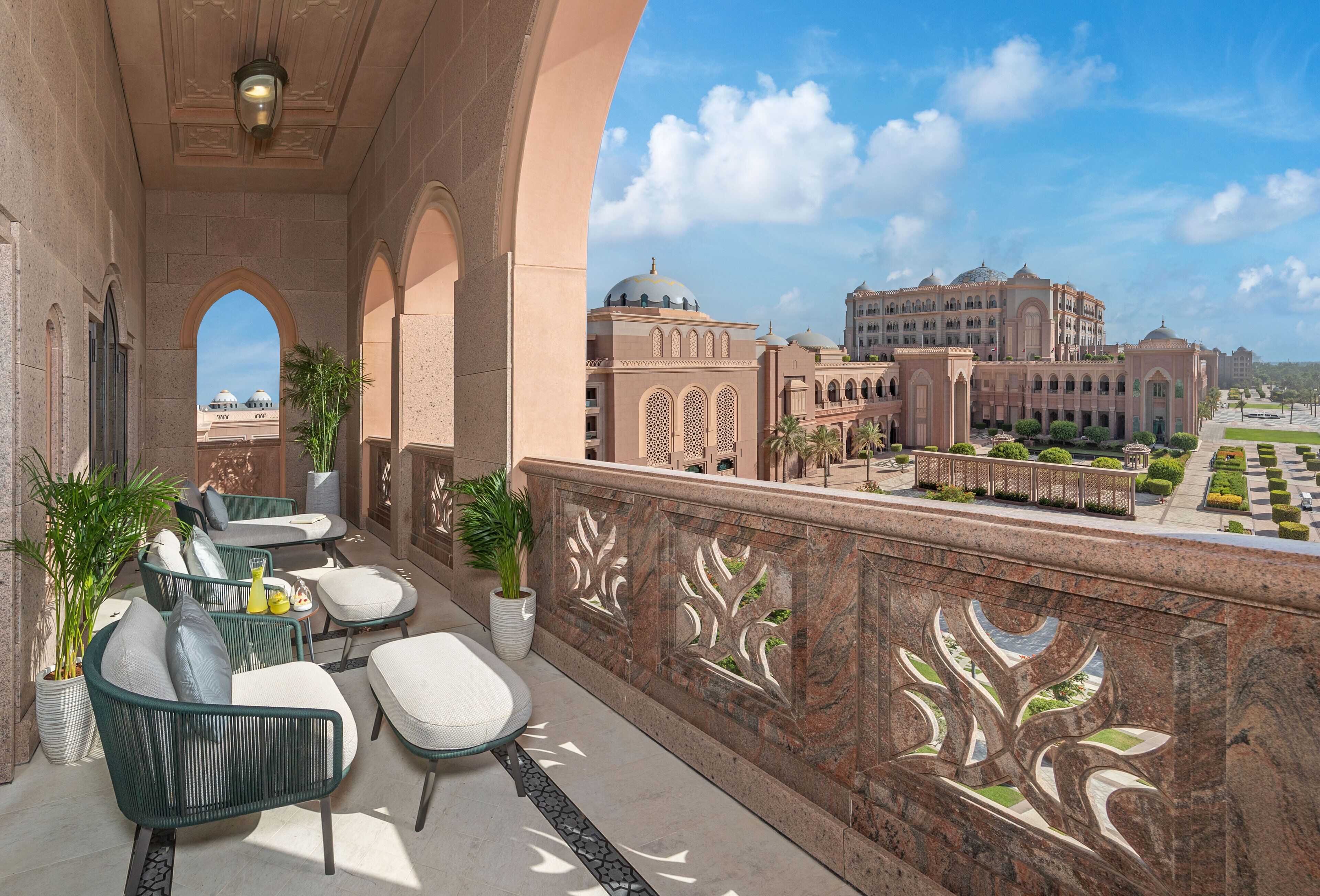 A balcony with outdoor seating, a decorative railing, and a view of a large building with domes.