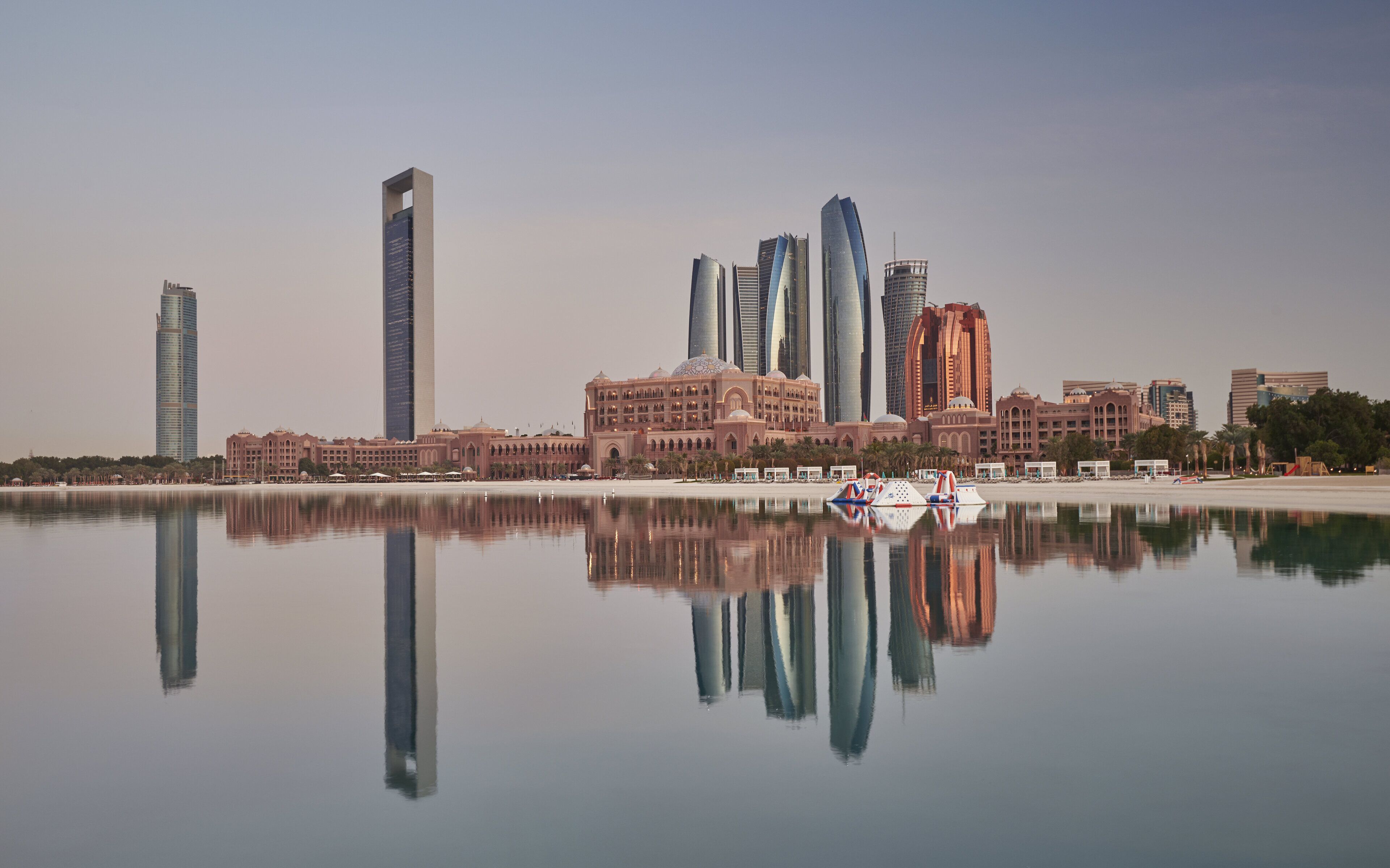 A city skyline with modern skyscrapers and a calm body of water reflecting the buildings.