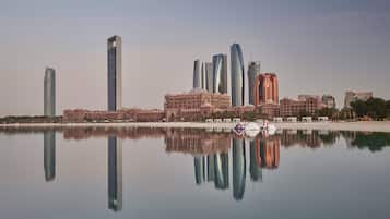 A city skyline with modern skyscrapers and a calm body of water reflecting the buildings.