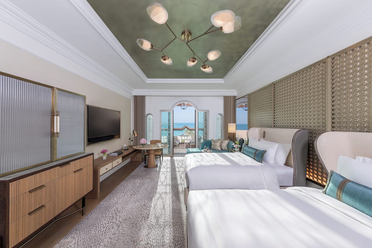 Ein geräumiges Hotelzimmer mit einem großen Bett, einem Fernseher, einem Schreibtisch und Meerblick.
