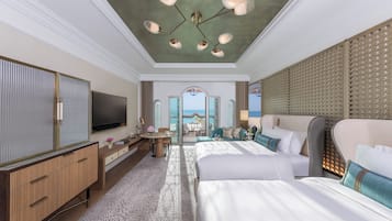 A spacious hotel room with a large bed, a TV, a desk, and a view of the sea.