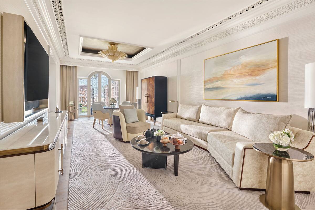 A spacious living room with a large sofa, a coffee table, and a television. There is a large window with a view of the city.