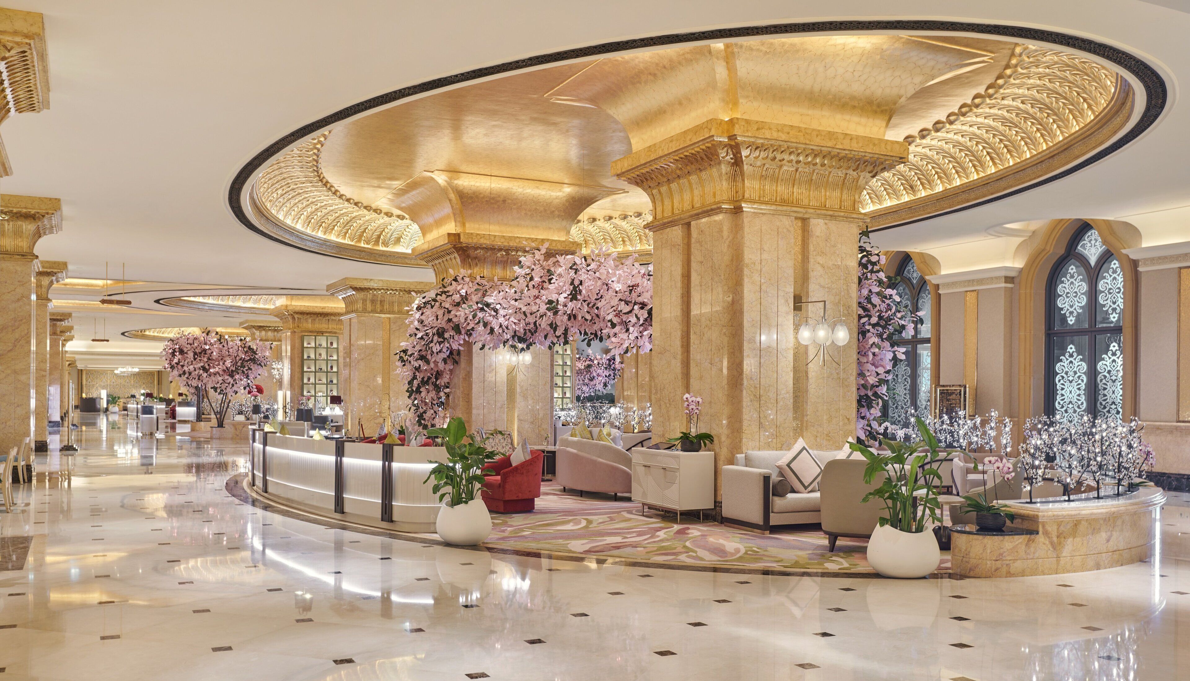 A luxurious lobby with marble floors, elegant seating, and floral decorations.
