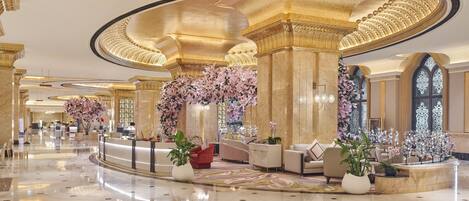 A luxurious lobby with marble floors, elegant seating, and floral decorations.