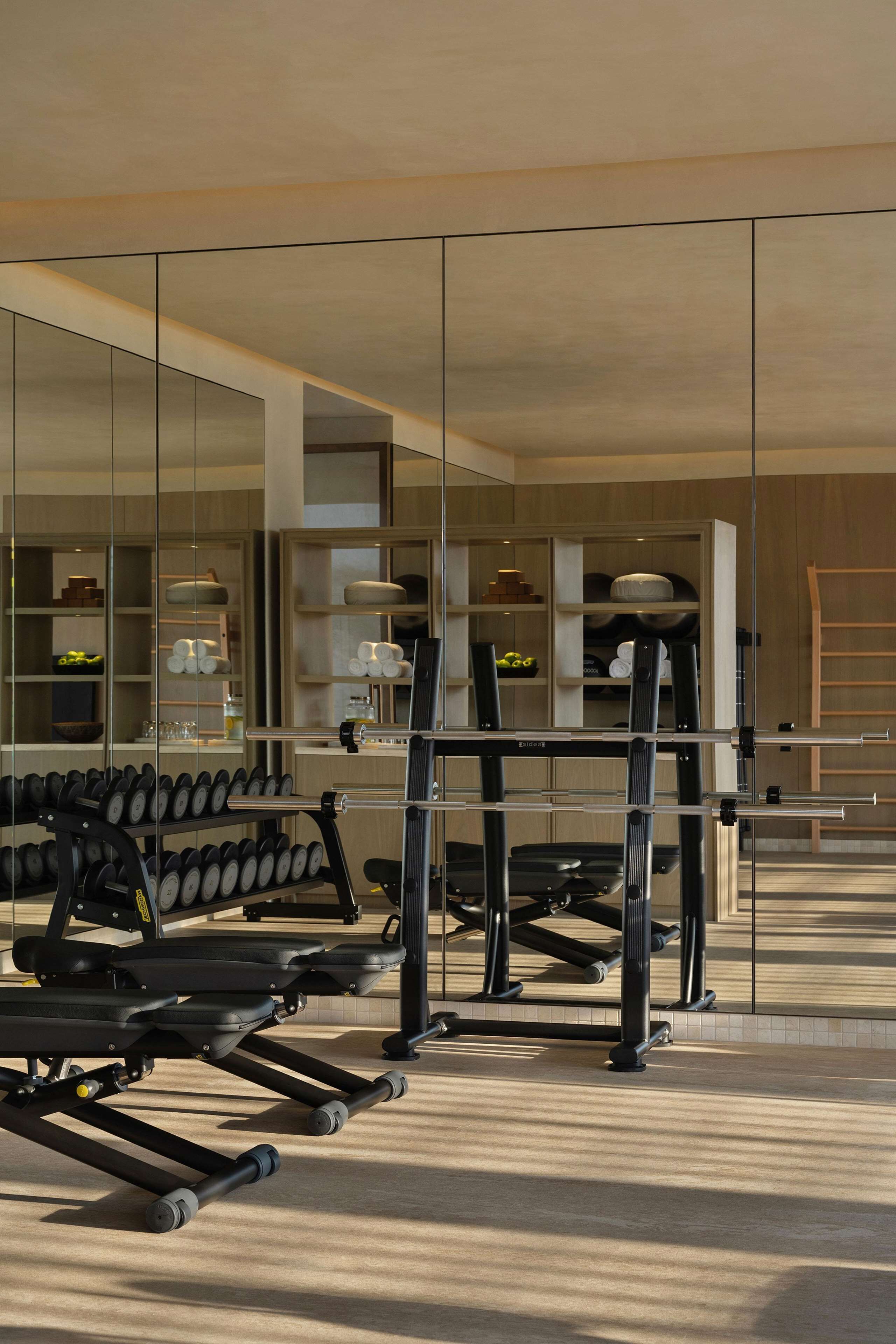 A gym with exercise equipment and a mirrored wall.
