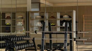 A gym with exercise equipment and a mirrored wall.