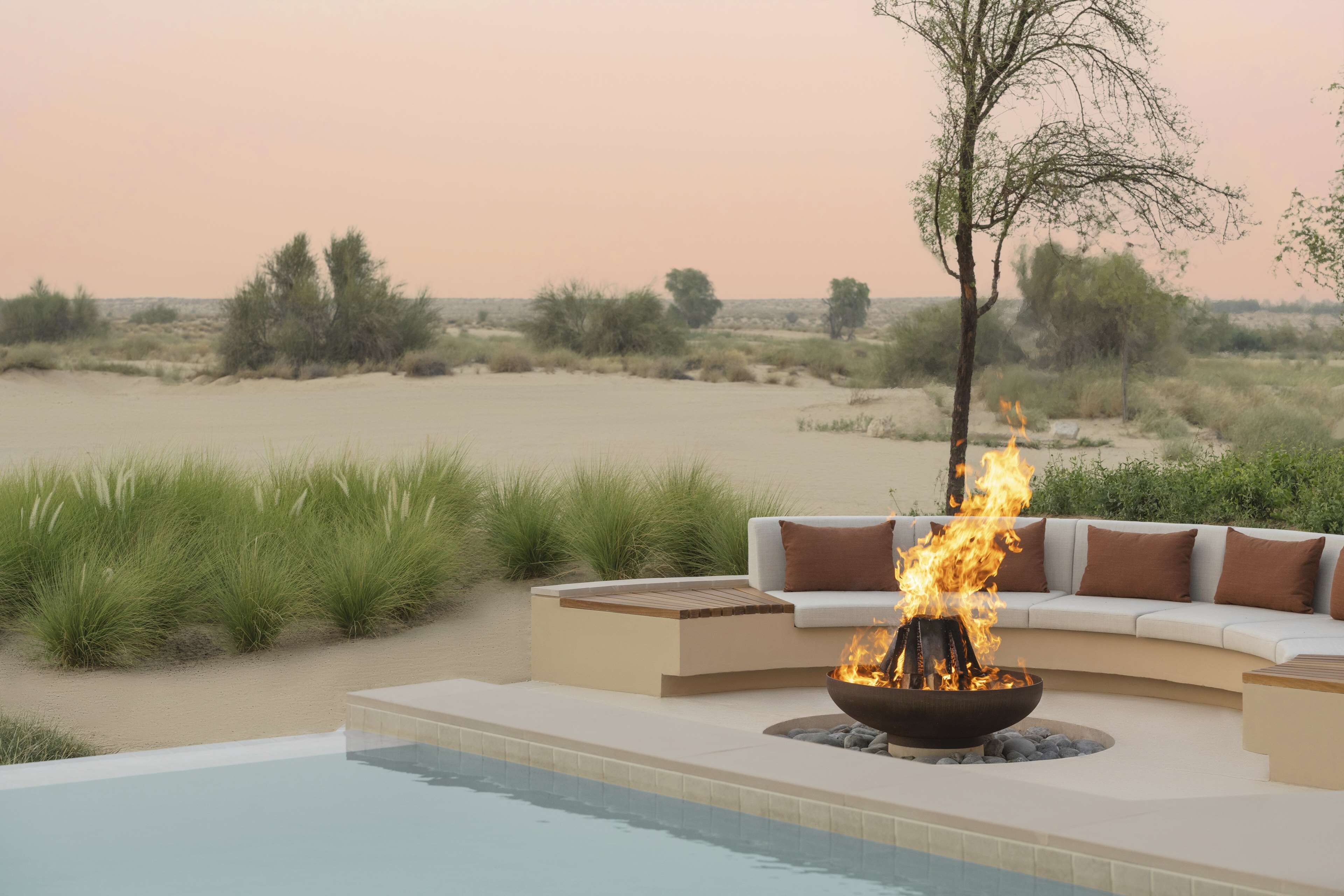 A poolside area with a fire pit and a sofa.