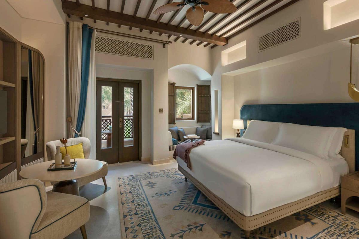 Habitació d'hotel amb un llit gran, una taula petita, una cadira i una nitzeta.