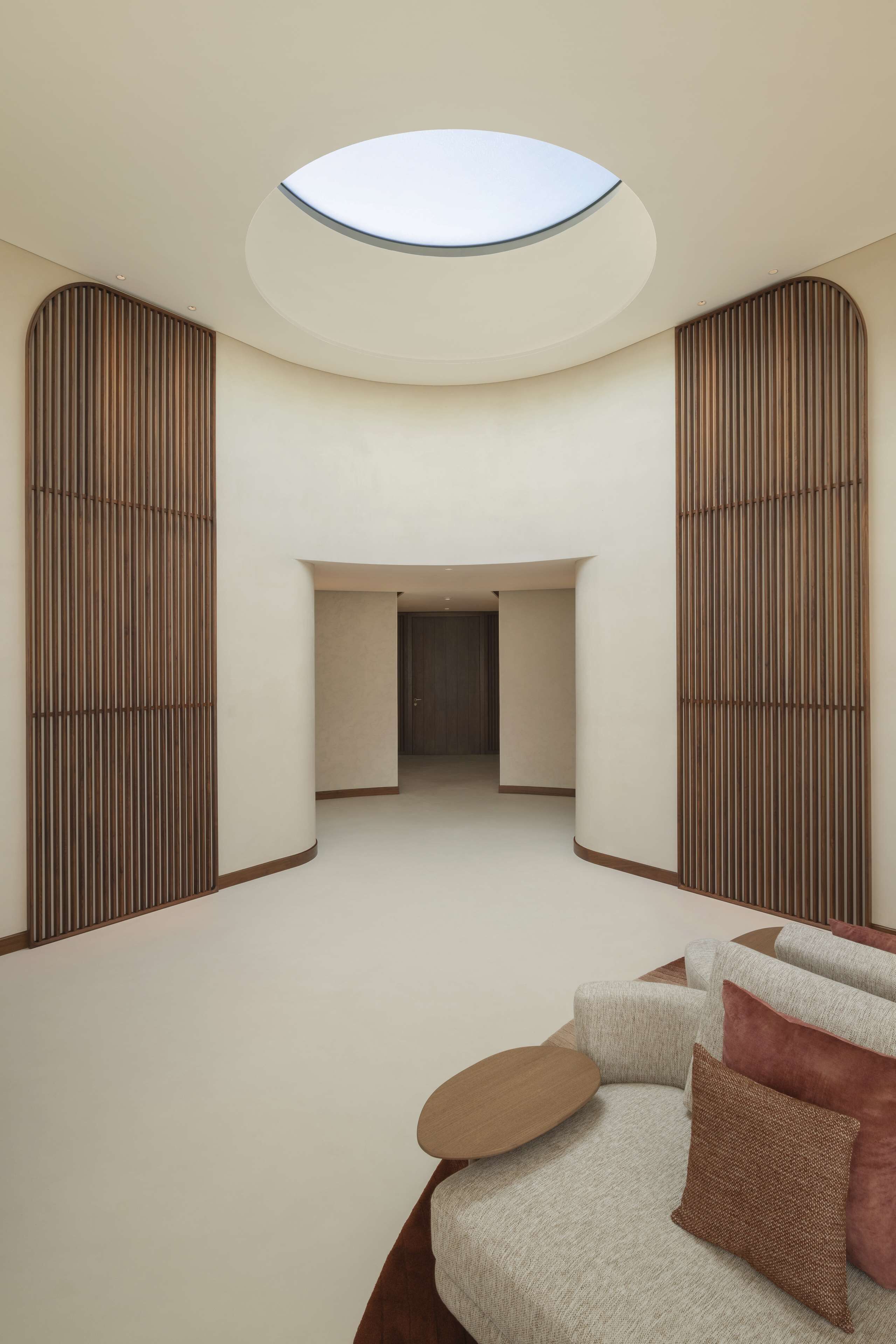 A modern interior with a circular skylight, a sofa with cushions, and a wooden floor.