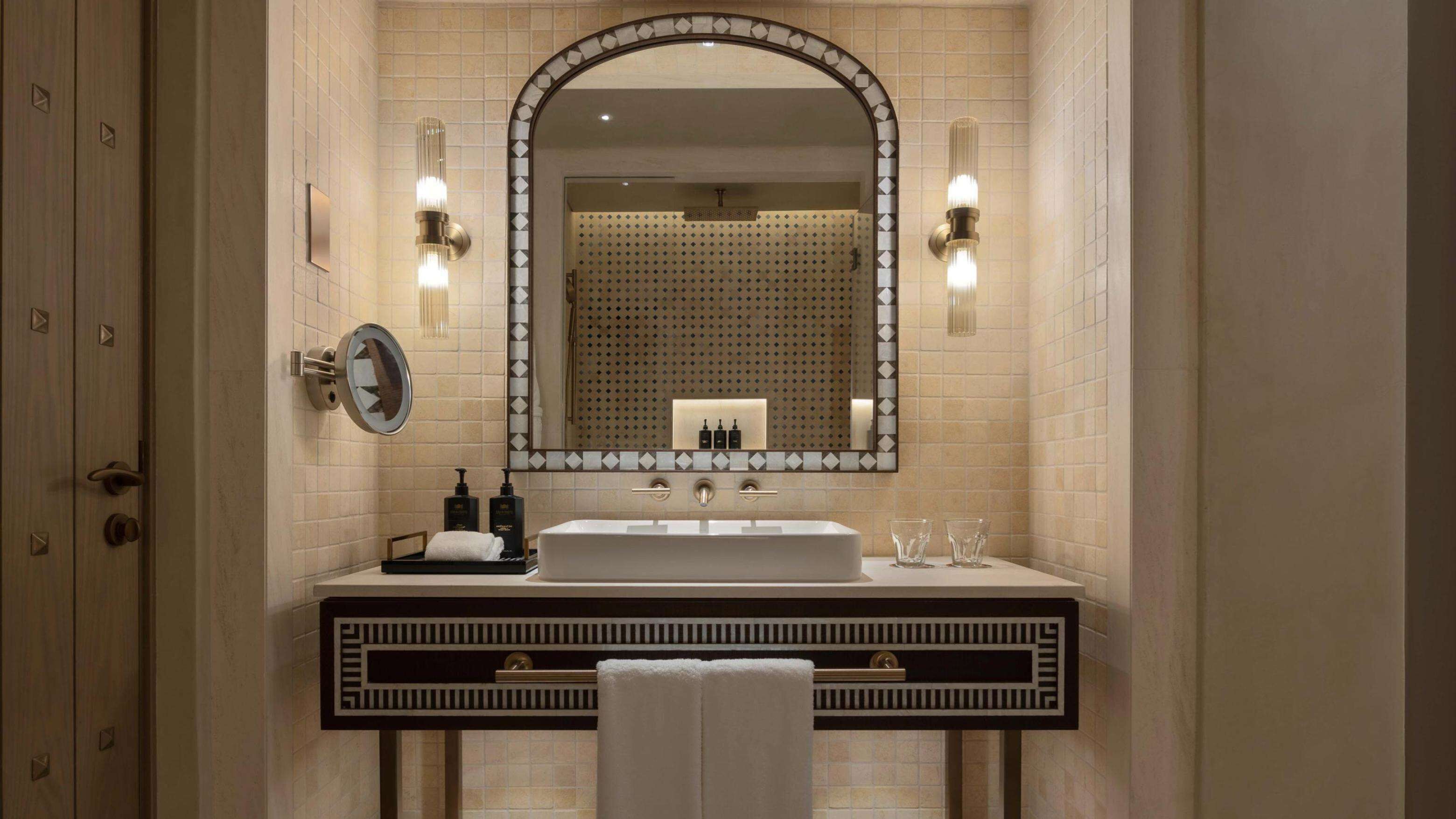 A modern bathroom with a large mirror, two sinks, and a towel rack.