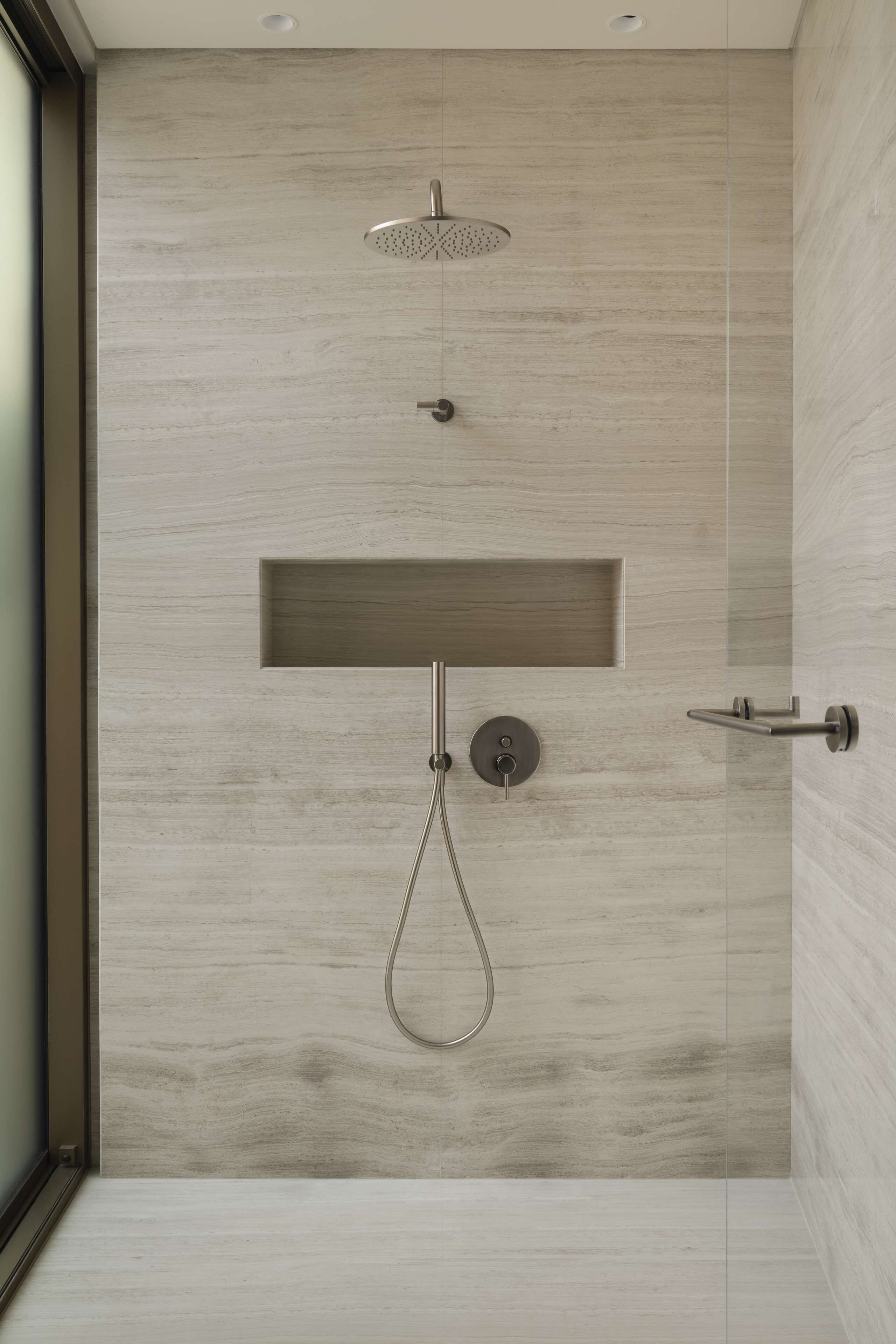 Une douche moderne dotée d’un pommeau de douche à pluie, d’un pommeau de douche à main et d’un panneau de commande fixé au mur.