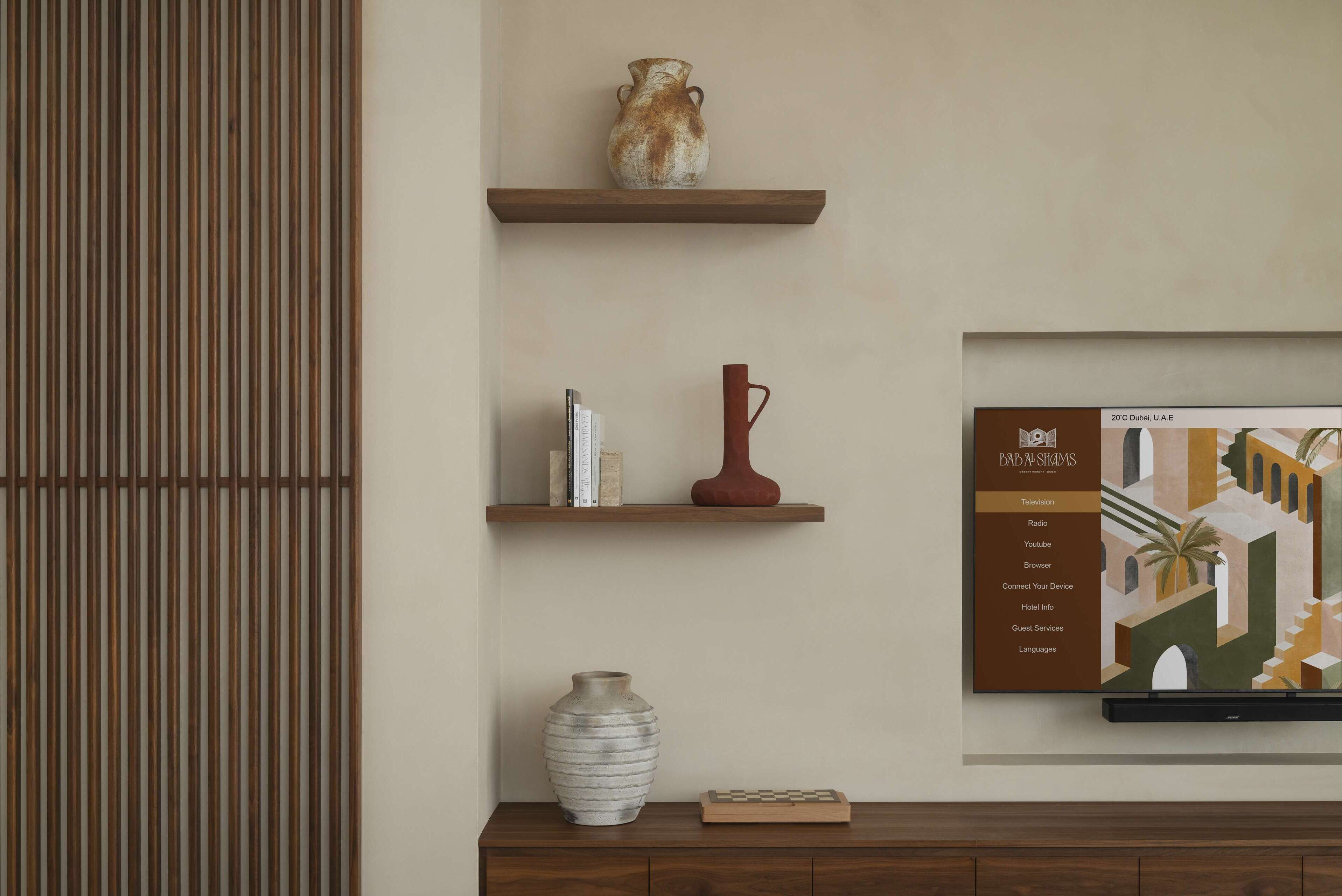 Un mur orné de trois étagères en bois, chacune portant des objets décoratifs tels que des vases et des livres. Une œuvre d’art encadrée est exposée sur le mur, à droite.