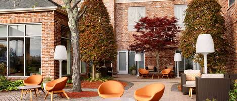 A courtyard with outdoor seating, brick walls, and potted plants.