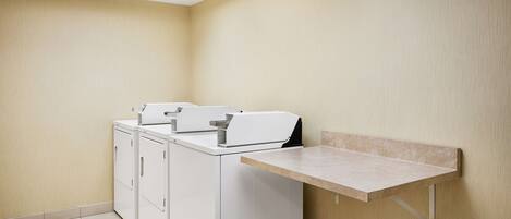 A laundry room with a washing machine and dryer, a small shelf, and a tiled floor.
