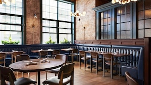 Un restaurant avec de grandes fenêtres, des tables en bois et des banquettes.