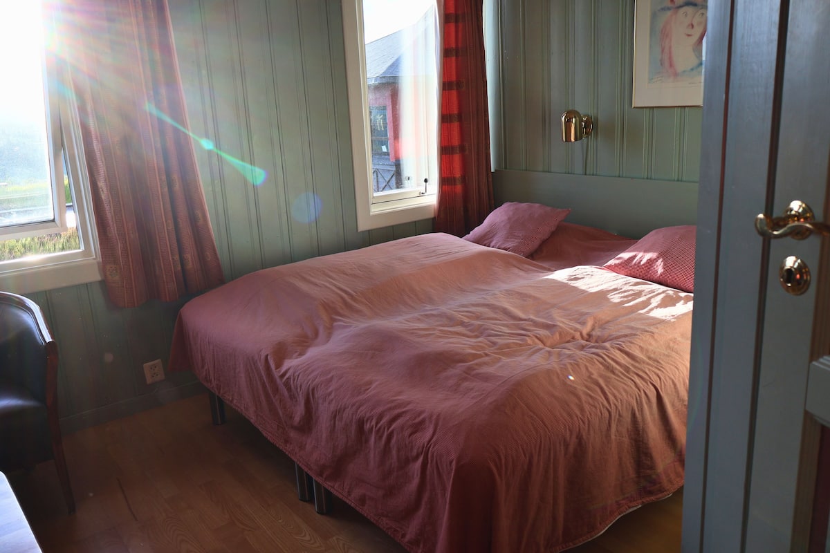 A bedroom with a bed, a window, a door, and a chair.