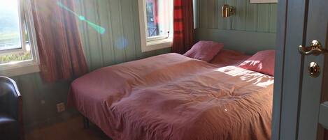Un dormitorio con cama, ventana, puerta y una silla.