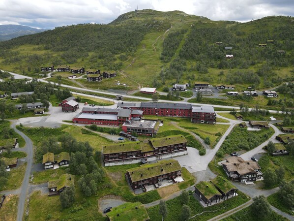 A large, red building with multiple sections, surrounded by smaller houses and greenery. - Rauland Høgfjellshotell (Vinje)