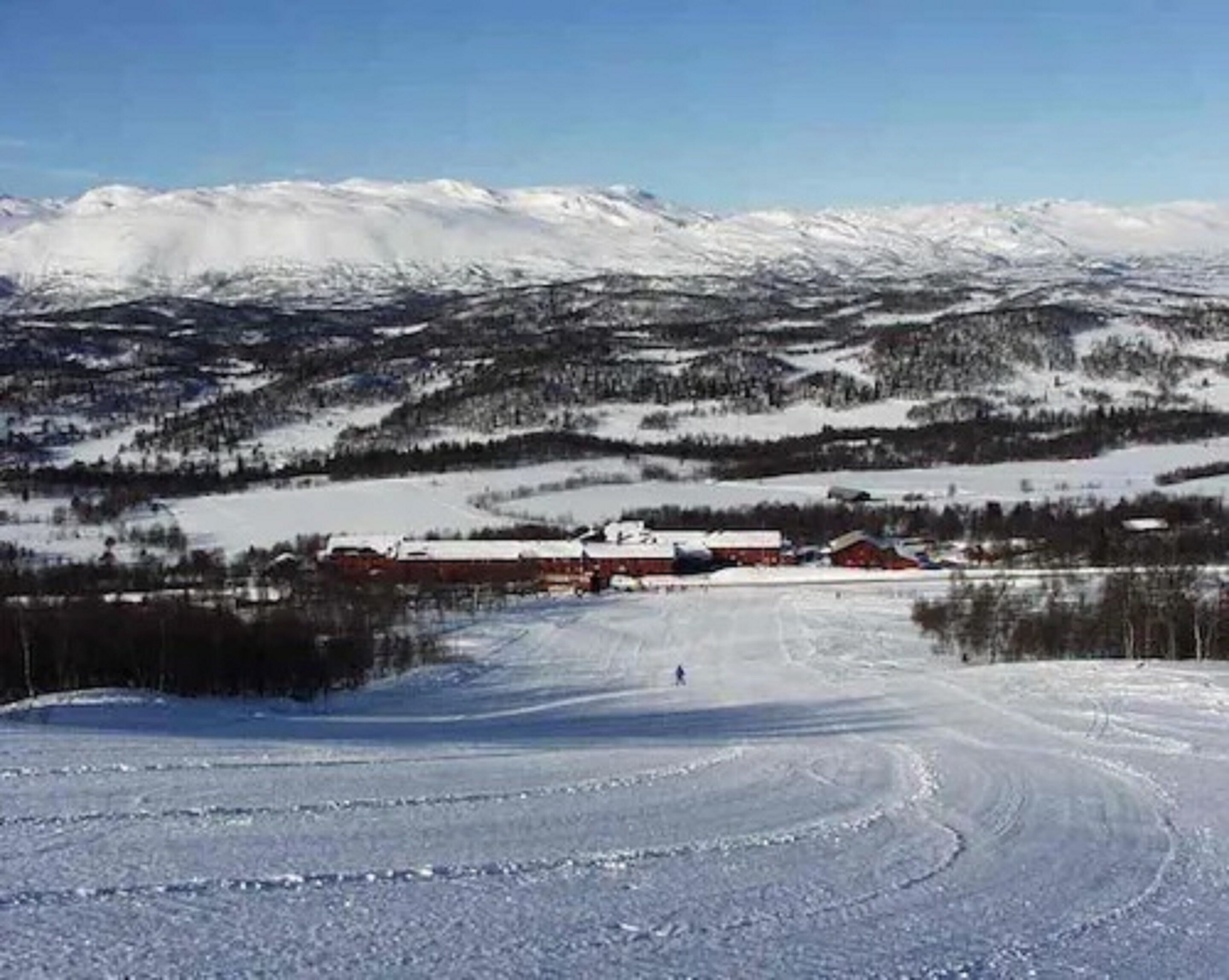 A snowy landscape with a building and a ski slope.