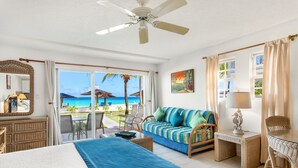 A hotel room with a bed, a sofa, a desk, and a view of the beach.