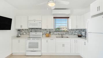 A modern kitchen with white cabinets, a built-in oven, a microwave, and a coffee maker.