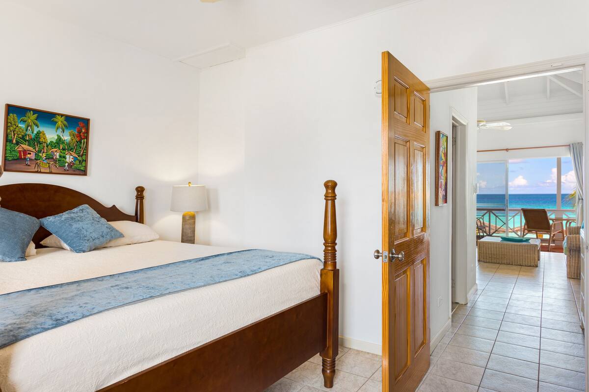 Een slaapkamer met een houten bed, een nachtkastje met een lamp en een schilderij aan de muur.