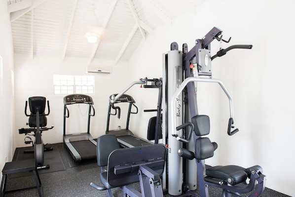 A gym with cardio machines, weight training equipment, and a bench.