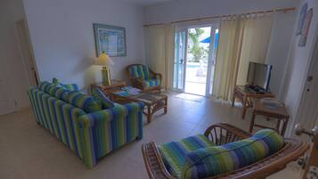A living room with striped sofas, a wicker chair, a table, and a television.