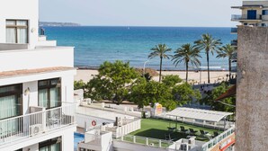Een hotel met een zwembad, uitzicht op zee en palmbomen.