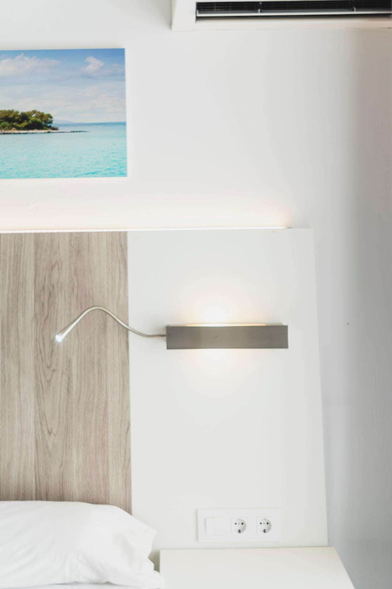 Un dormitorio moderno con cabecera de madera, una mesita de noche y una lámpara de pared.